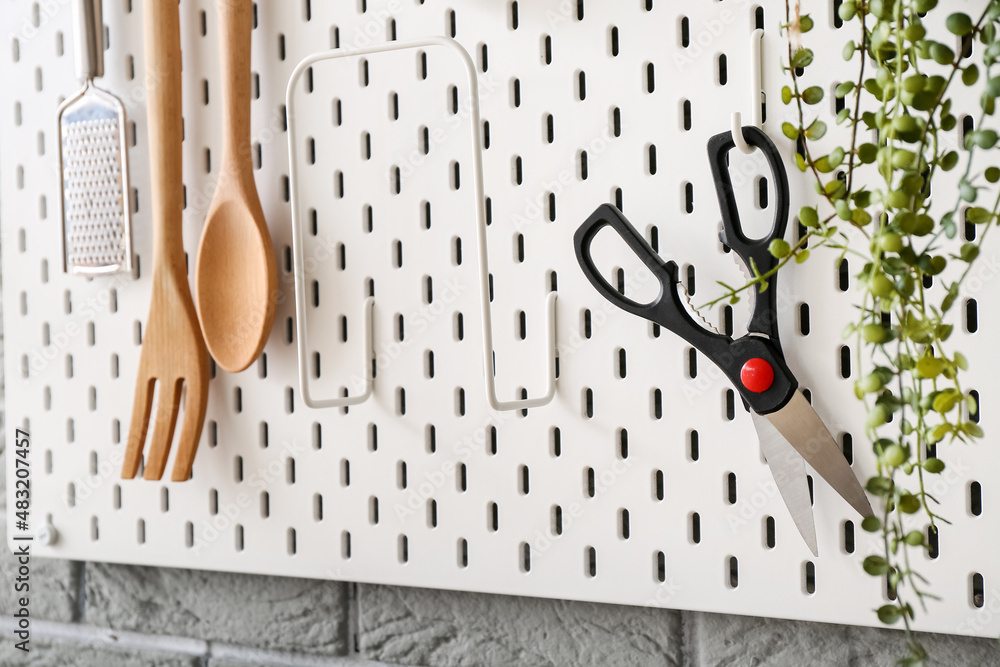 Pegboard with scissors and houseplant, closeup