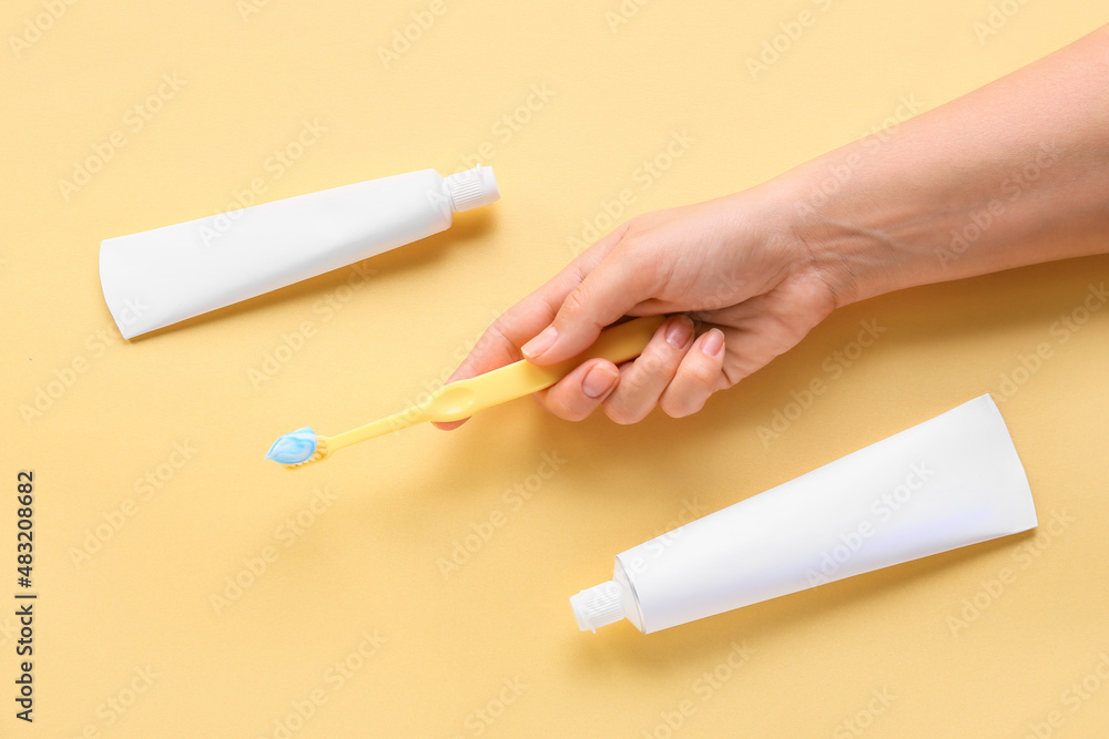 Female hand with tooth brush and paste on beige background