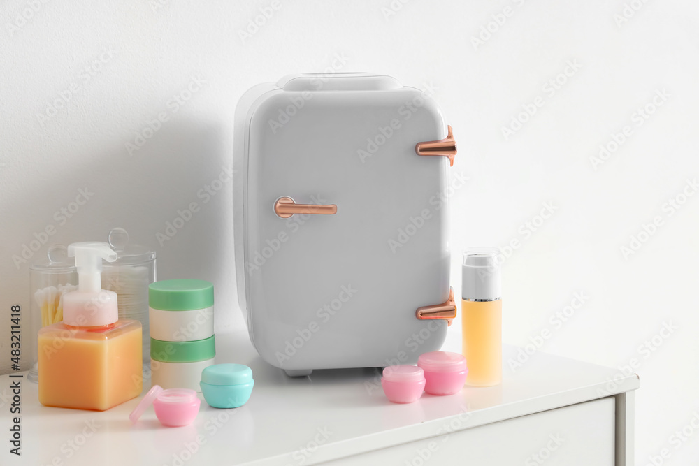 Small cosmetic refrigerator and products on shelf near light wall