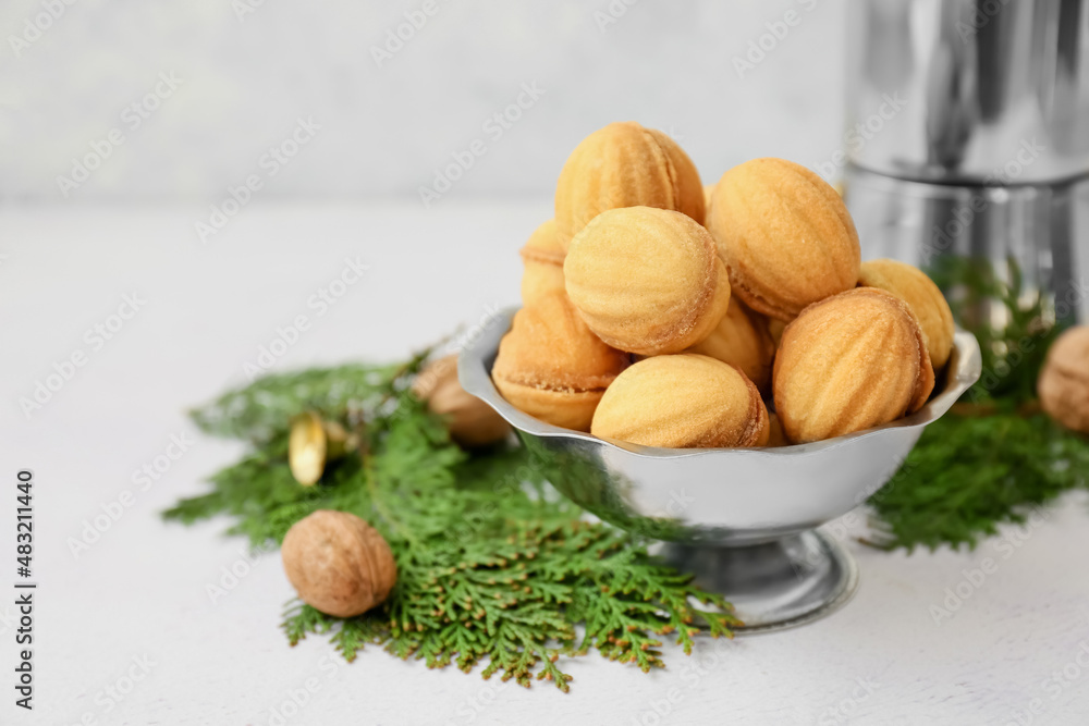 Bowl of tasty walnut shaped cookies with boiled condensed milk and thuja branches on light backgroun