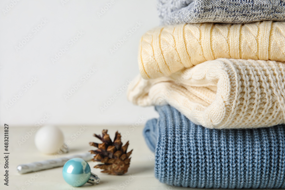 Stylish baby sweaters and Christmas decor on light background, closeup