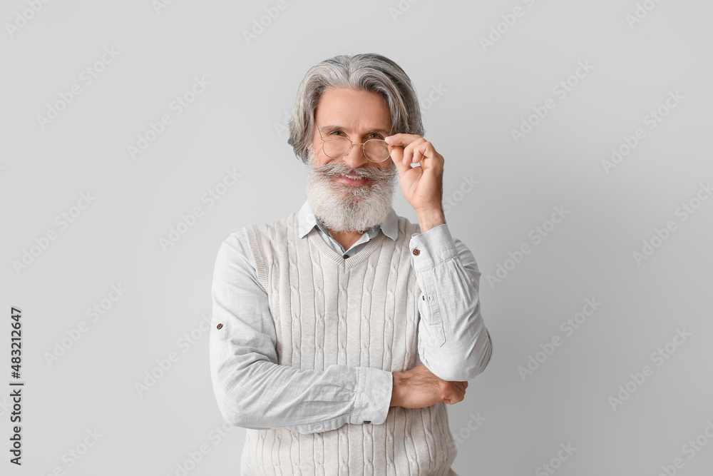 Senior man in eyeglasses on light background