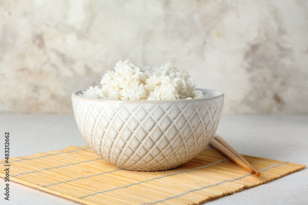 Bowl with tasty boiled rice and chopsticks on light background, closeup