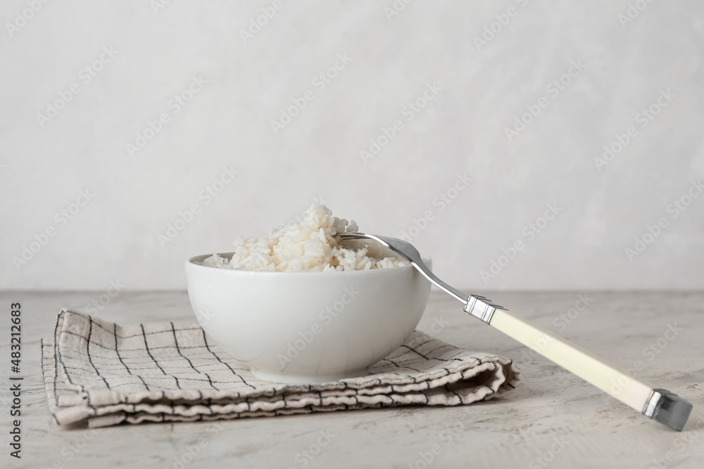 Bowl with tasty boiled rice on light background