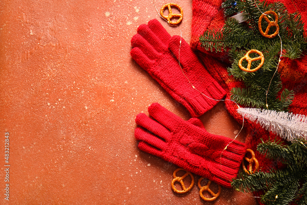 Warm gloves, fir branches and Christmas lights on red background