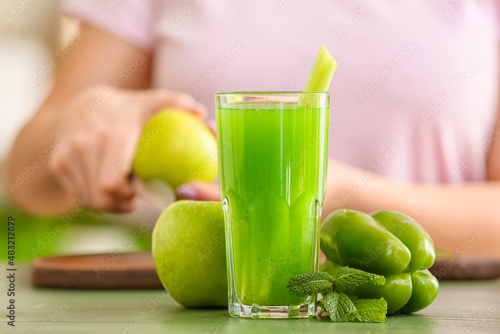 Glass of healthy green juice and fresh ingredients on table against blurred background