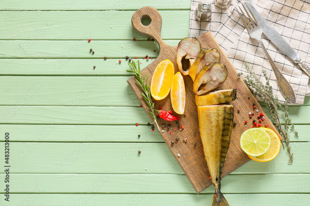 Board with cut smoked mackerel fish on green wooden background