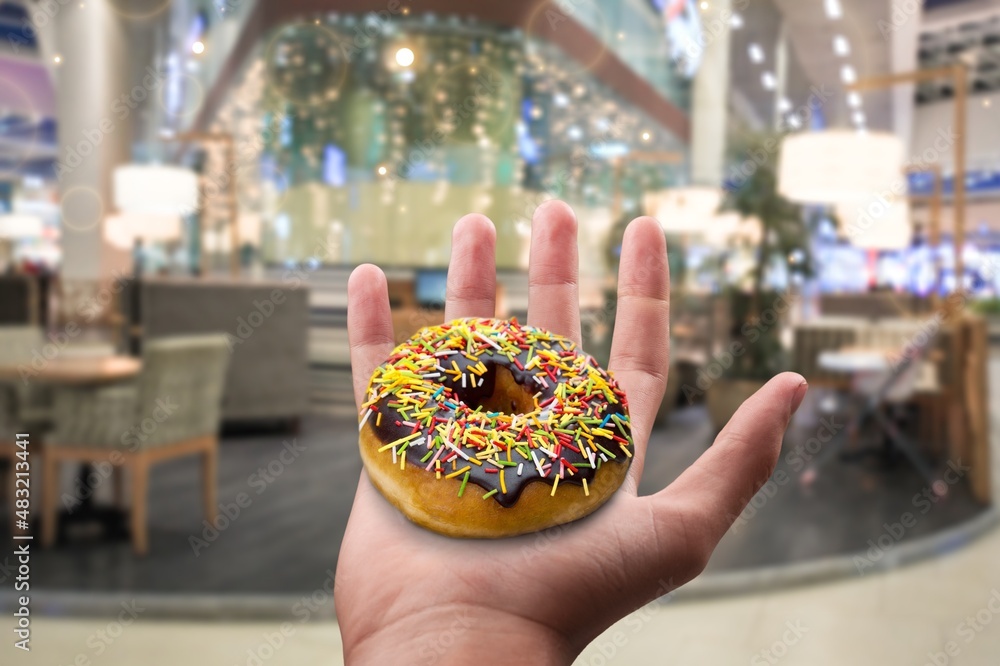 Hand holds Hanukkah donut with jam on the background.