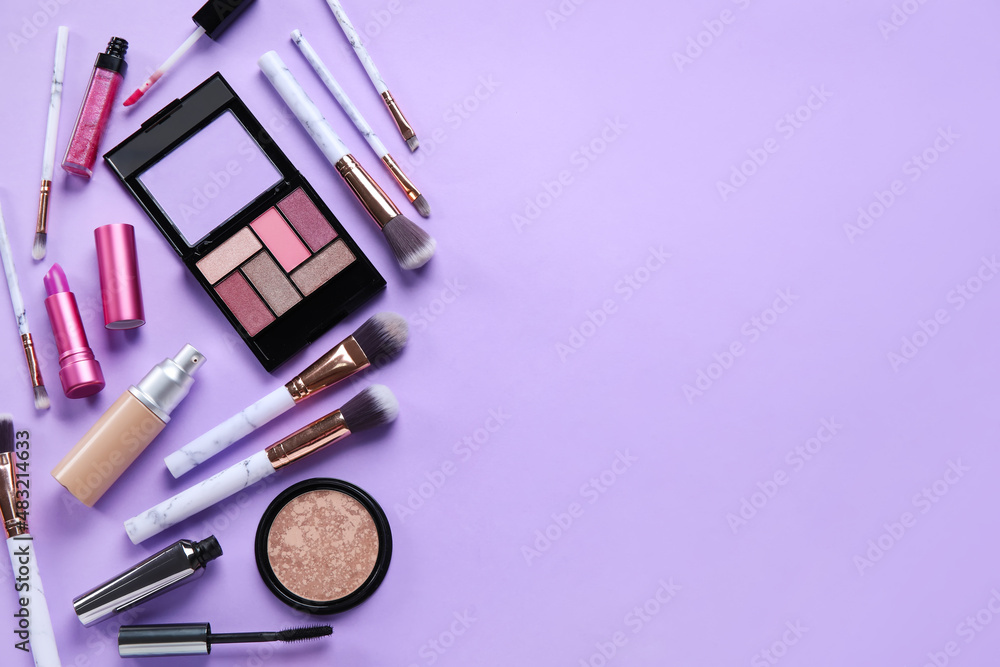 Different makeup products on purple background