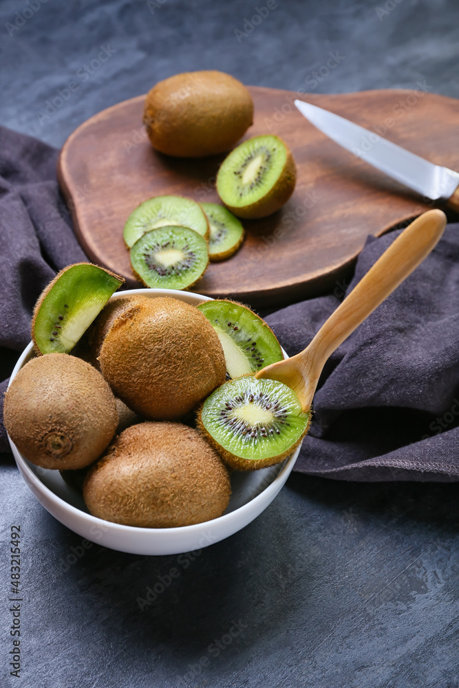 Bowl with fresh ripe kiwi on dark background, closeup