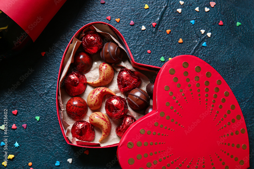 Heart shaped box with tasty chocolate candies on black background