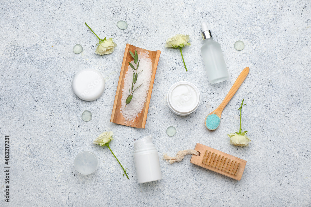 Different cosmetic products and rose flowers on light background