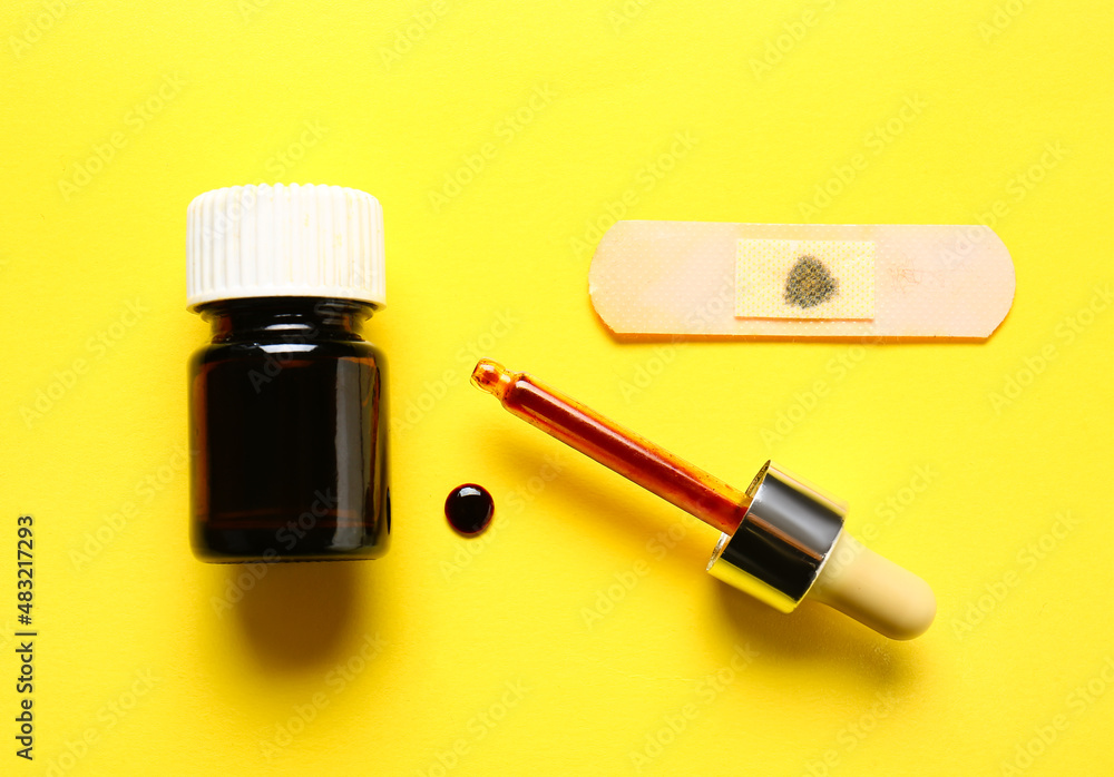 Bottle with iodine, pipette and medical plaster on yellow background