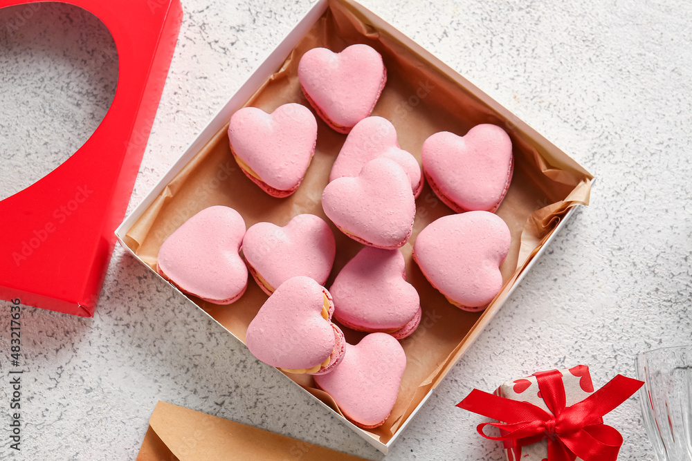 Box with tasty heart-shaped macaroons on light background