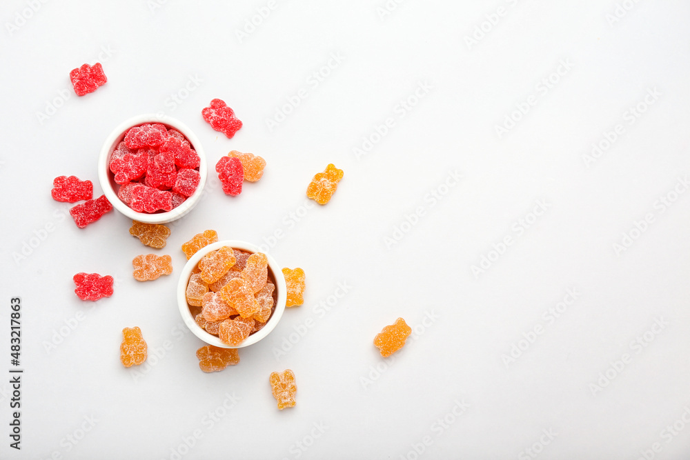 Bowls with tasty jelly bears on white background