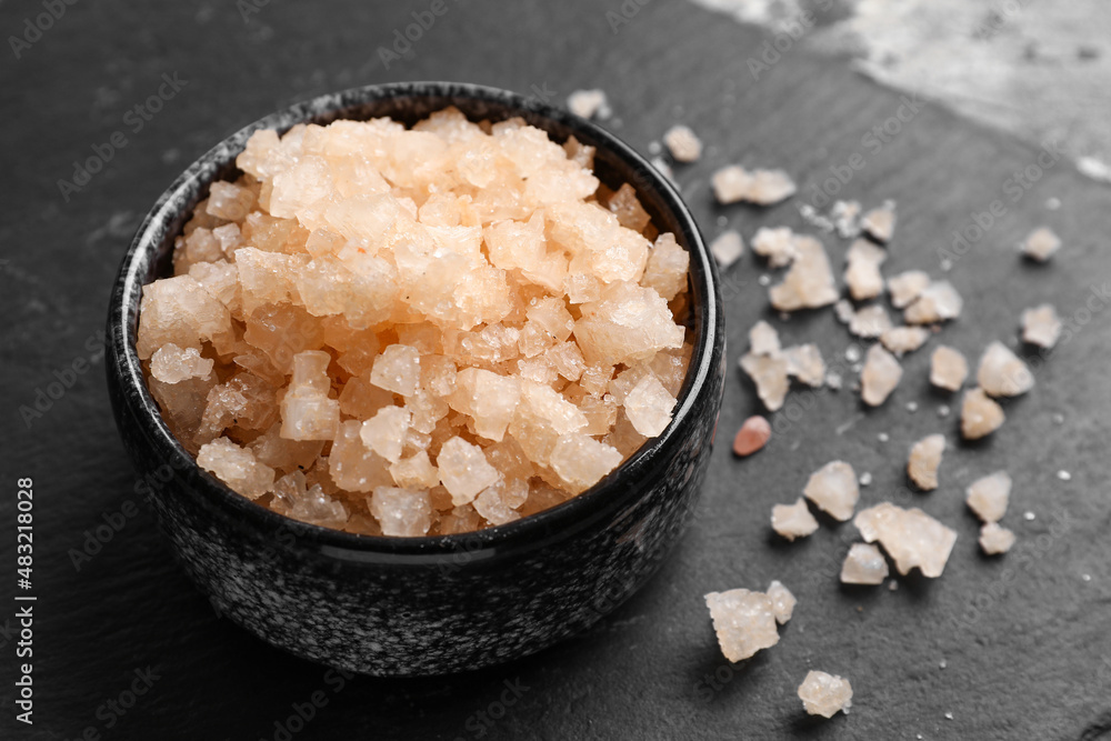 Bowl of sea salt on dark background, closeup