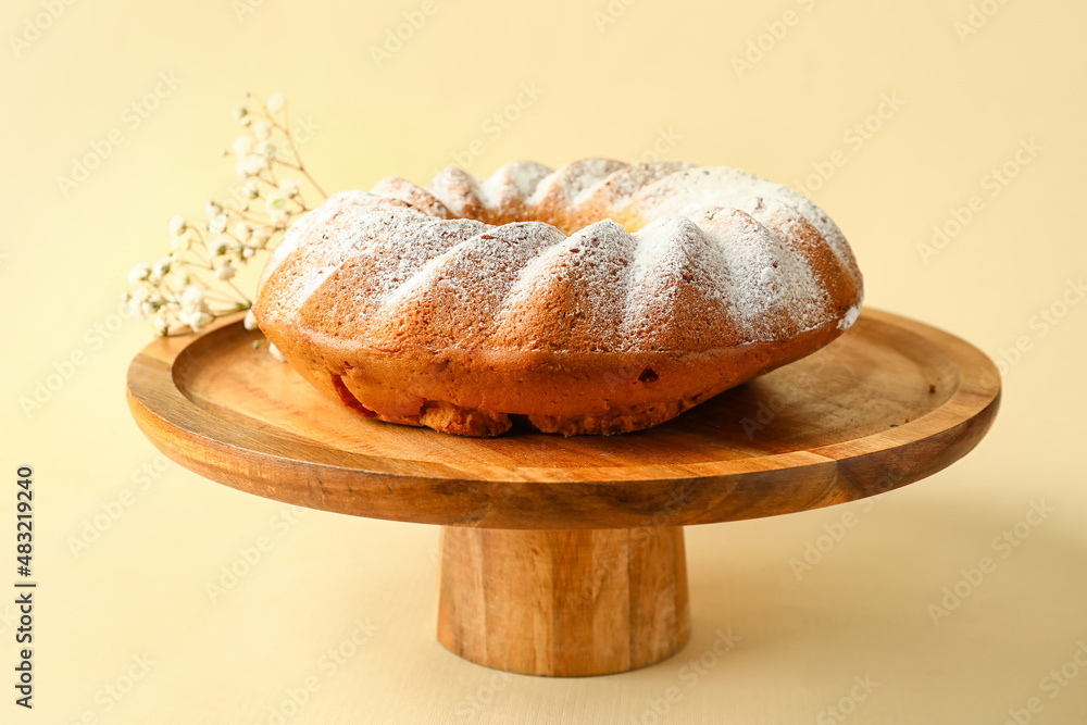 Dessert stand with tasty Easter cake on beige background