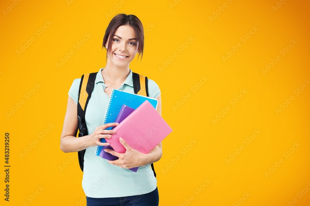 Smiling woman student with school books in hands on the background.