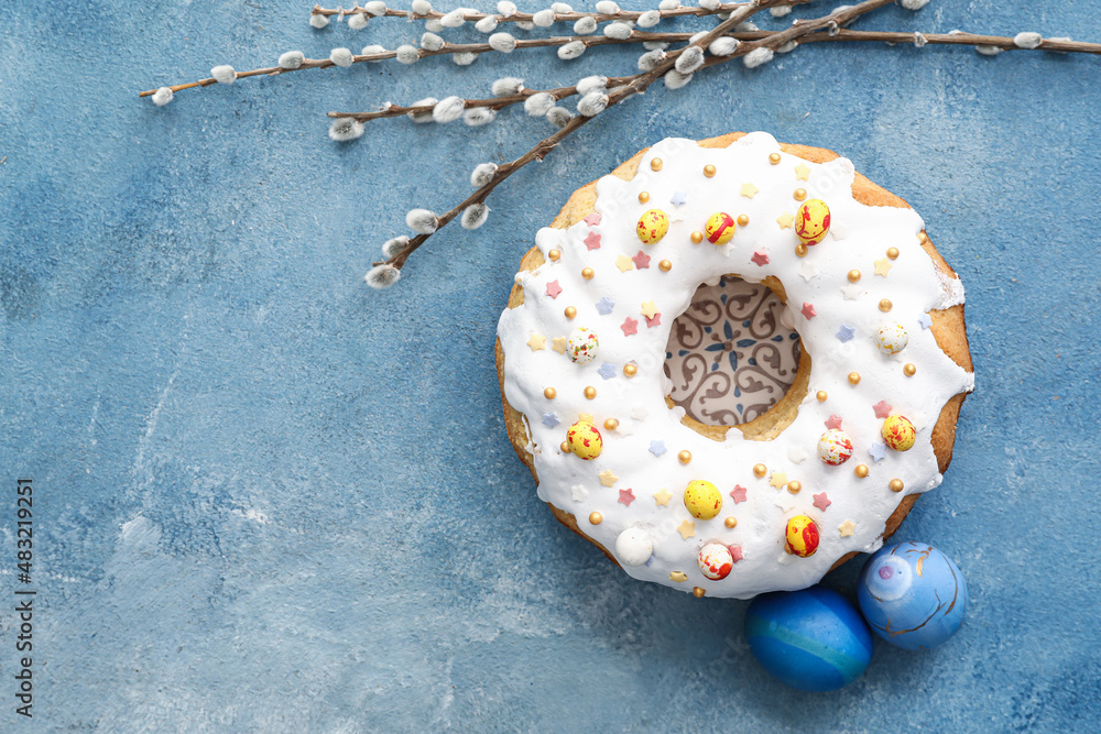 Tasty Easter cake, pussy willow branches and eggs on blue background