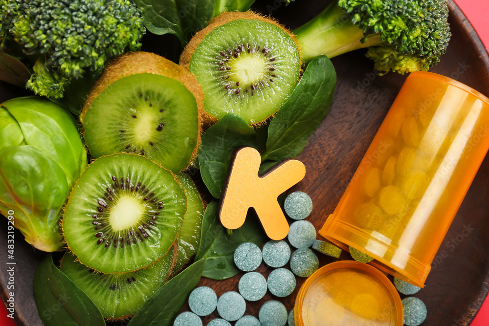 Plate with healthy products, bottle of pills and letter K, closeup