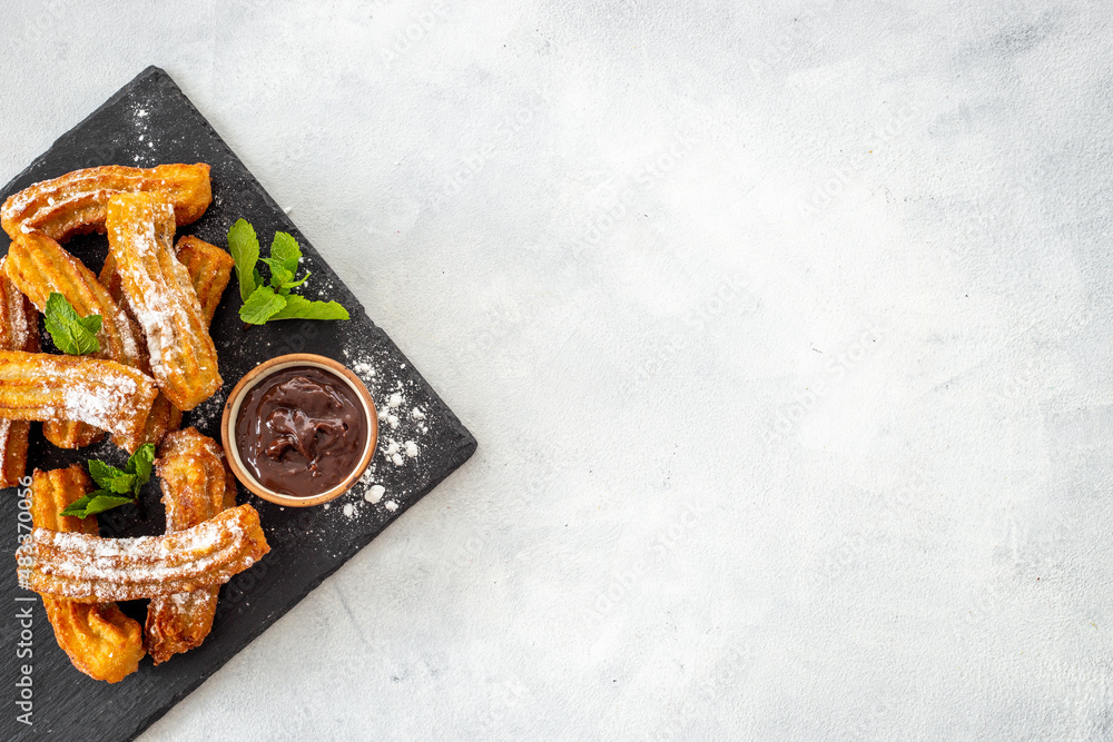 Churros with powdered sugar and chocolate sauce. Fast food sweets