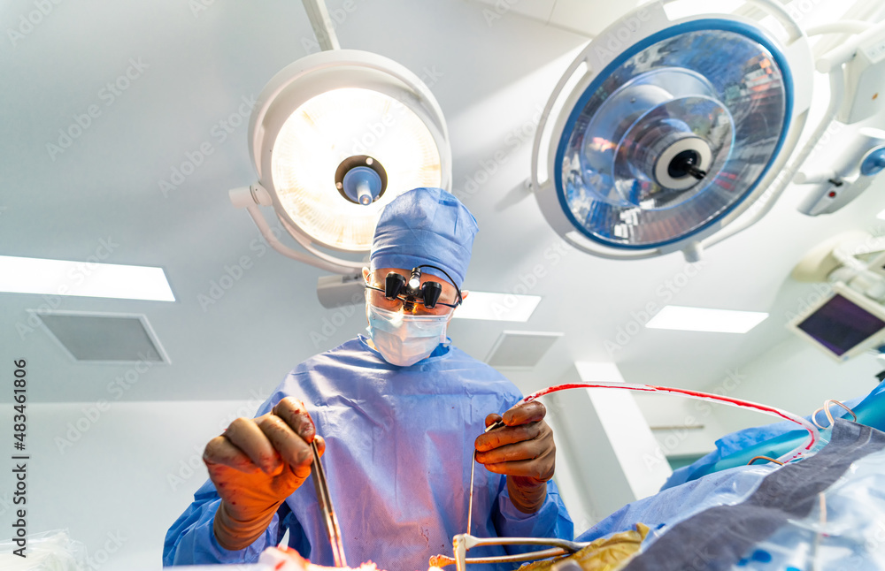 Neurosurgeon in special surgery glasses provides operation. Careful attentive doctor in operating ro