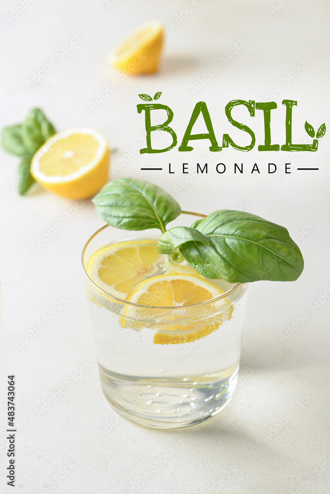 Glass of tasty basil lemonade on light background