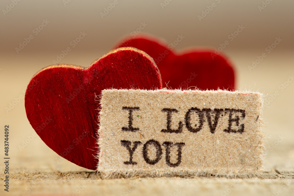 I love you - phrase typed. Valentines Day greetings concept. Little red wooden heart close up. Valen