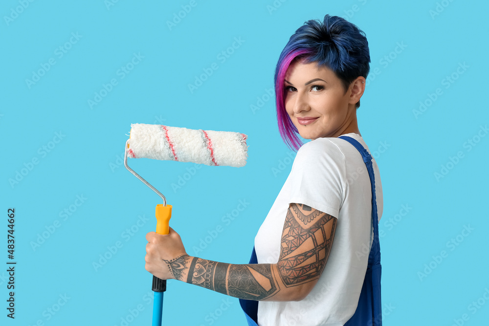 Female painter with bright hair and paint roller on blue background