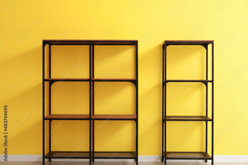 Modern empty standing shelving unit near yellow wall