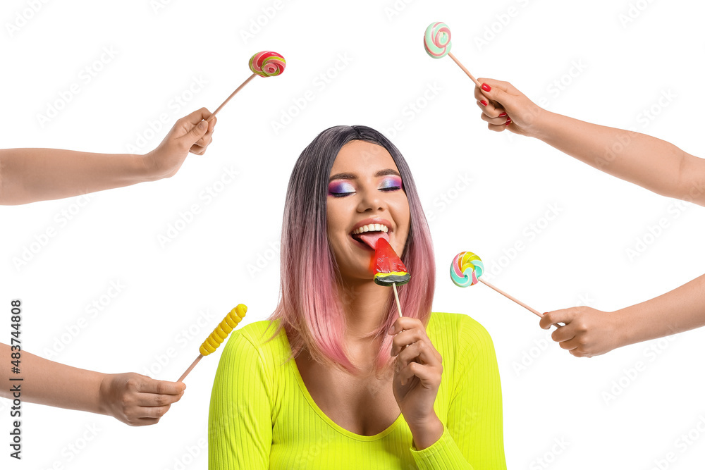 Young woman in wig and female hands with lollipops on white background