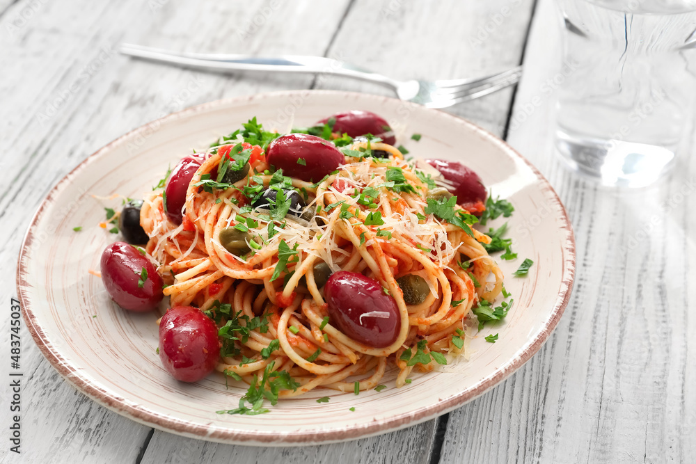 Plate of tasty Pasta Puttanesca on white wooden background