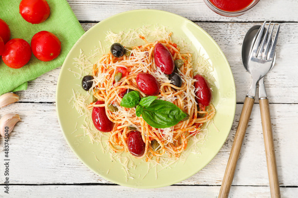 Plate of tasty Pasta Puttanesca on white wooden background