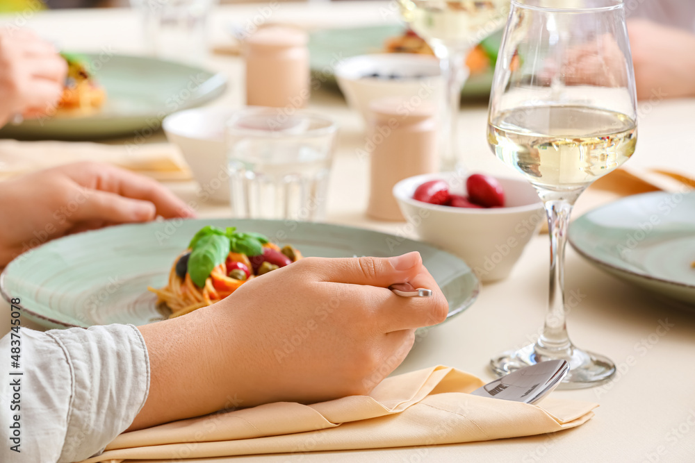 Woman eating delicious Pasta Puttanesca at table in restaurant