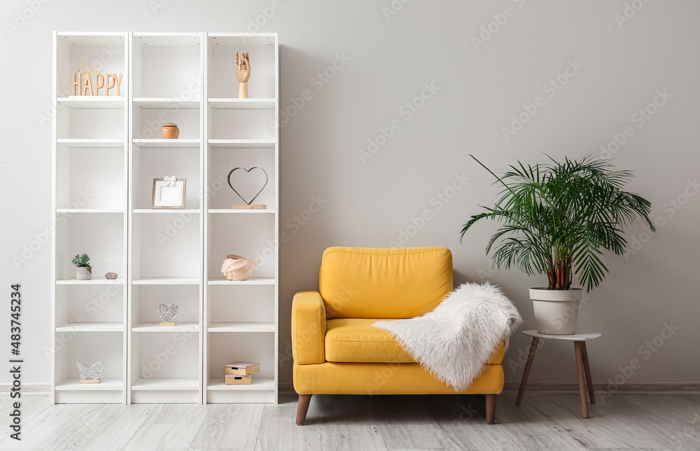 Yellow armchair with houseplant and shelving unit near light wall