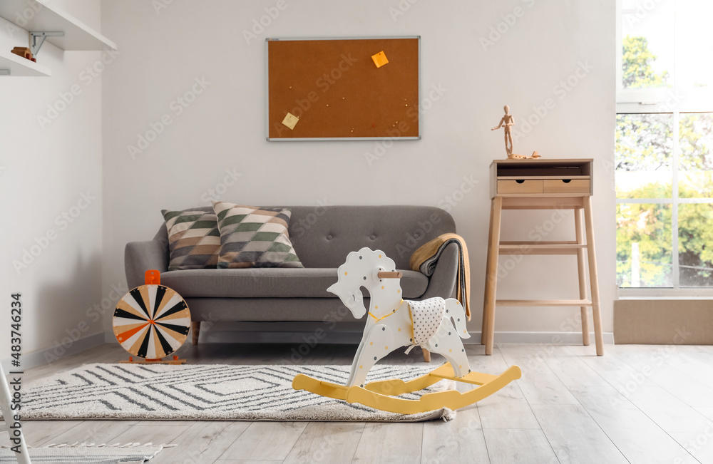 Rocking horse near sofa in light childs room