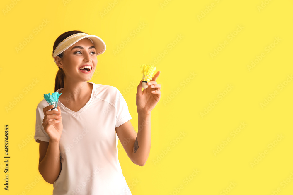 Happy female badminton player on yellow background