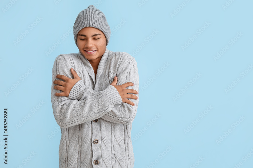 Handsome African-American guy in knitted sweater on color background