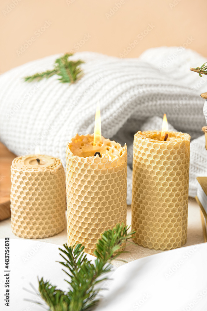 Burning candles, sweater and fir branch on table, closeup