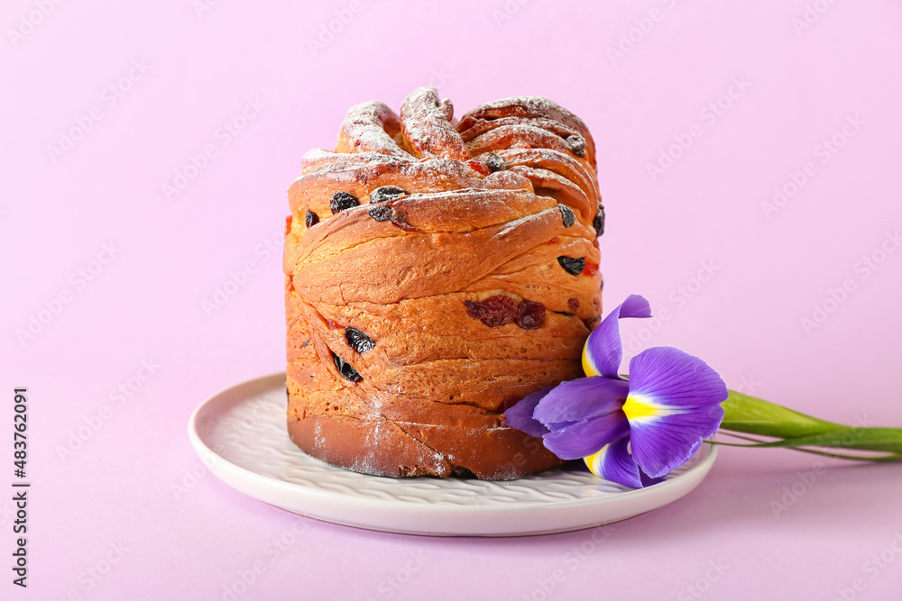 Plate with delicious Easter cake and iris flower on pink background