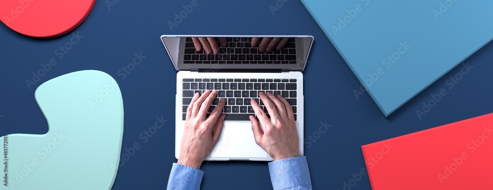 Person using a laptop computer with geometric shaped objects from above