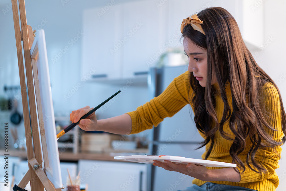 Asian young talented woman artist coloring on painting board in house. 