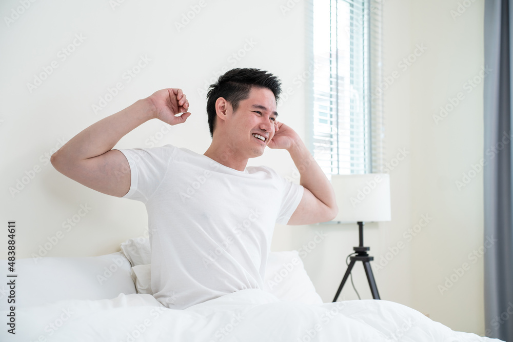 Asian handsome male in pajamas wake up in the morning with happiness. 