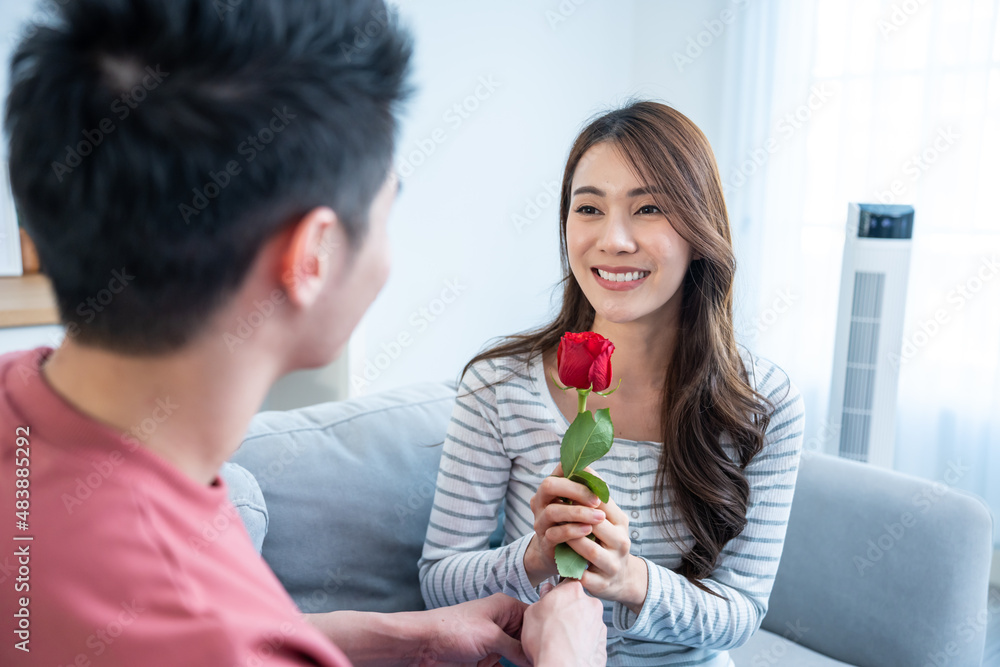 Asian young man surprise and give rose flower to beautiful girlfriend. 