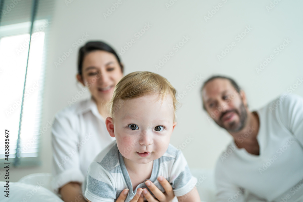 白人父母在家里的床上和可爱的男婴玩耍。