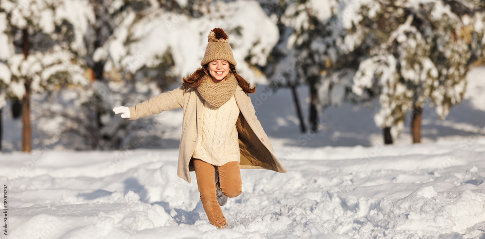 Happy child girl runs through а snowy winter park