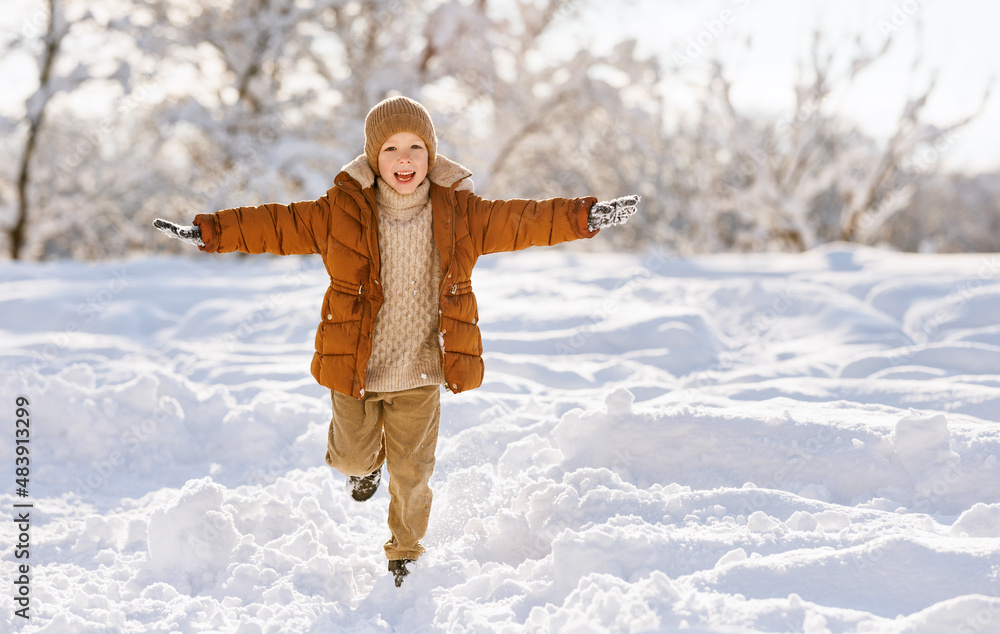 Happy child boy runs through а snowy winter park