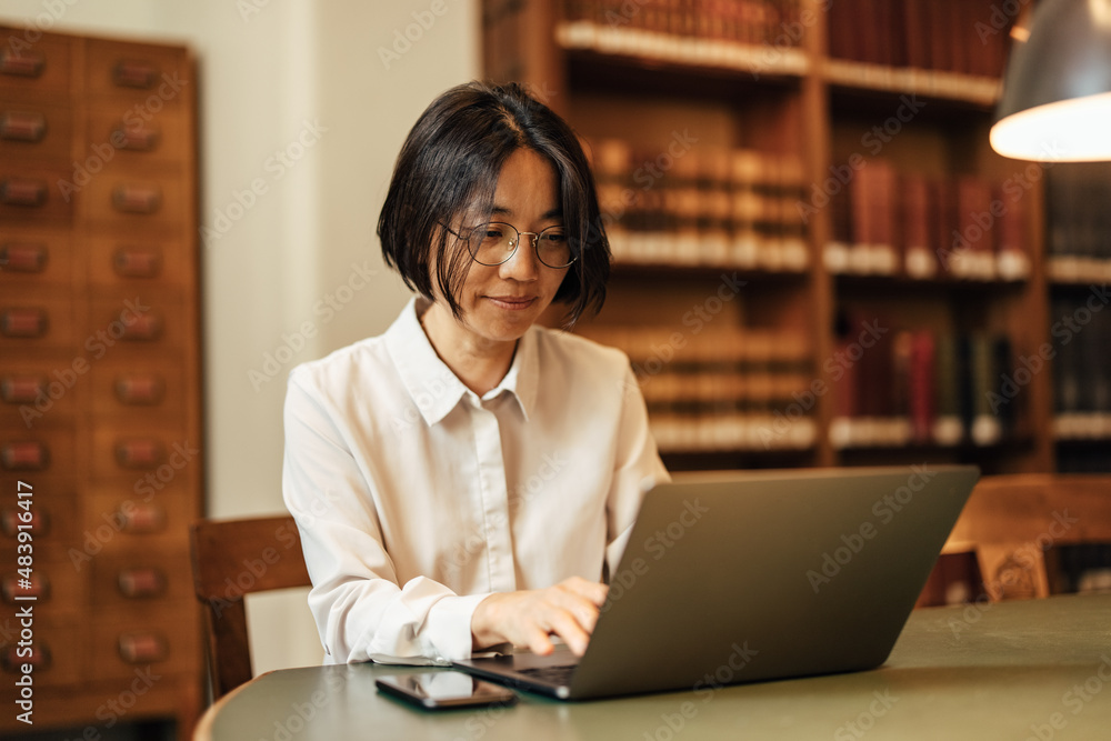 Ambitious adult, the Asian woman, working in an open coworking space