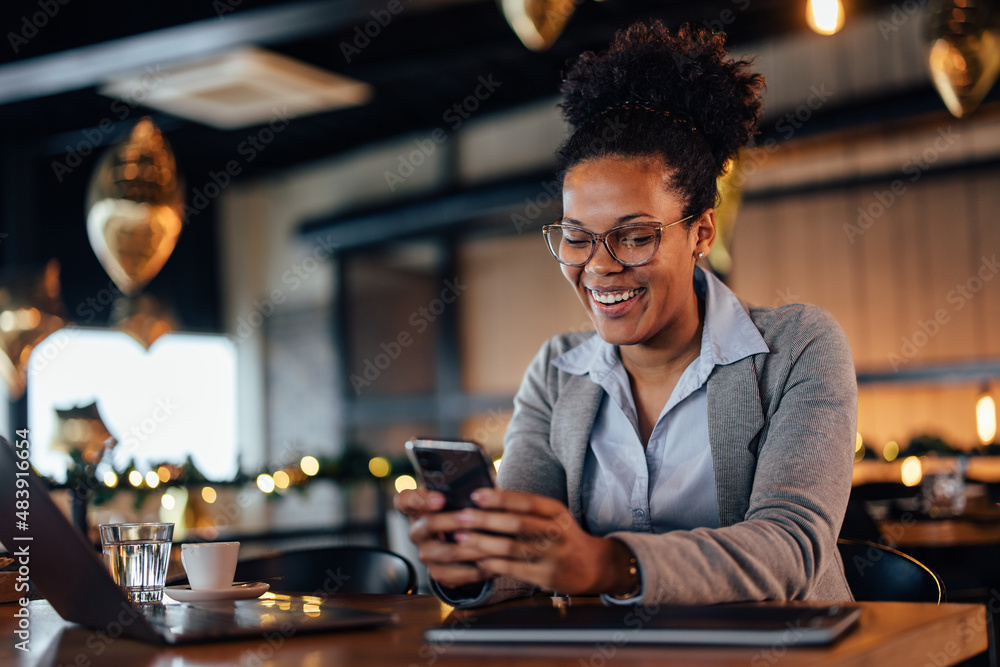 Smiling African-American woman, laughing at the joke she received on her phone.