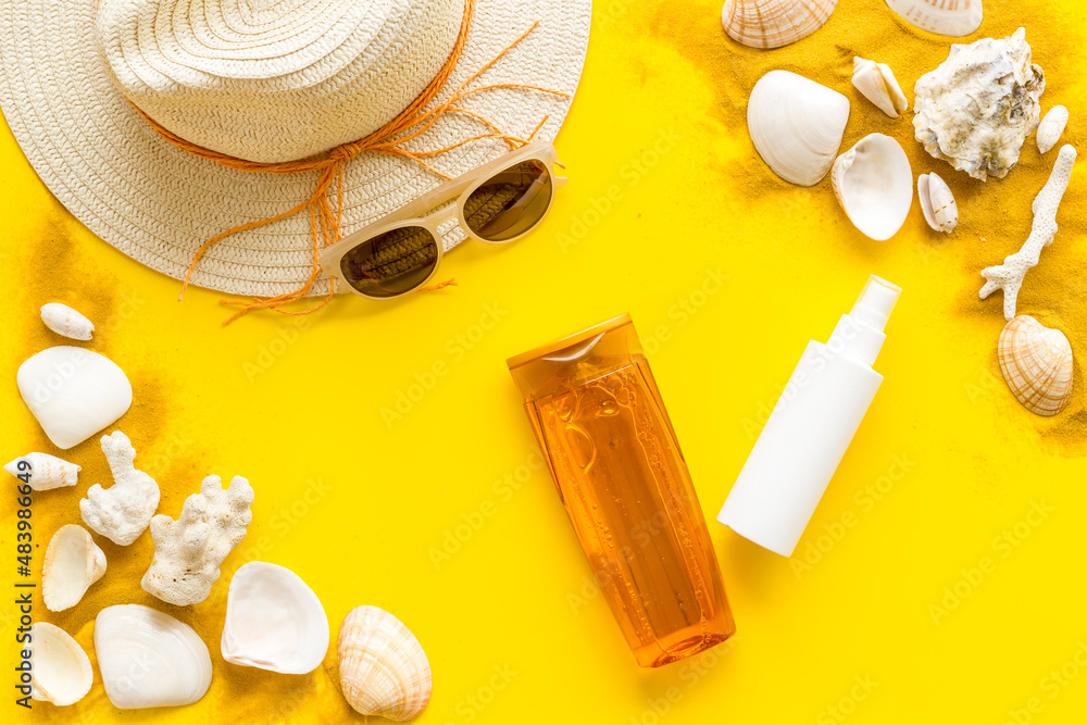 Sunscreen lotion on towel and suglasses with straw hat